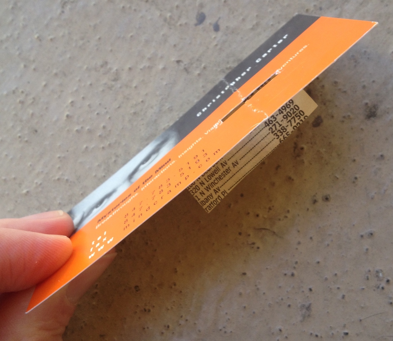 a photo of a business card with a piece of phone-book paper taped to the back of it